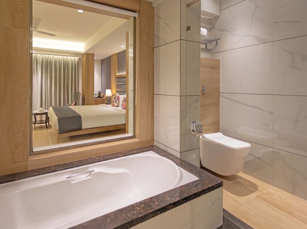 Ett modernt hotellbadrum med ett stort badkar, en separat toalett och en duschavdelning med glasväggar.