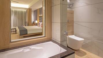 Ett modernt hotellbadrum med ett stort badkar, en separat toalett och en duschavdelning med glasväggar.