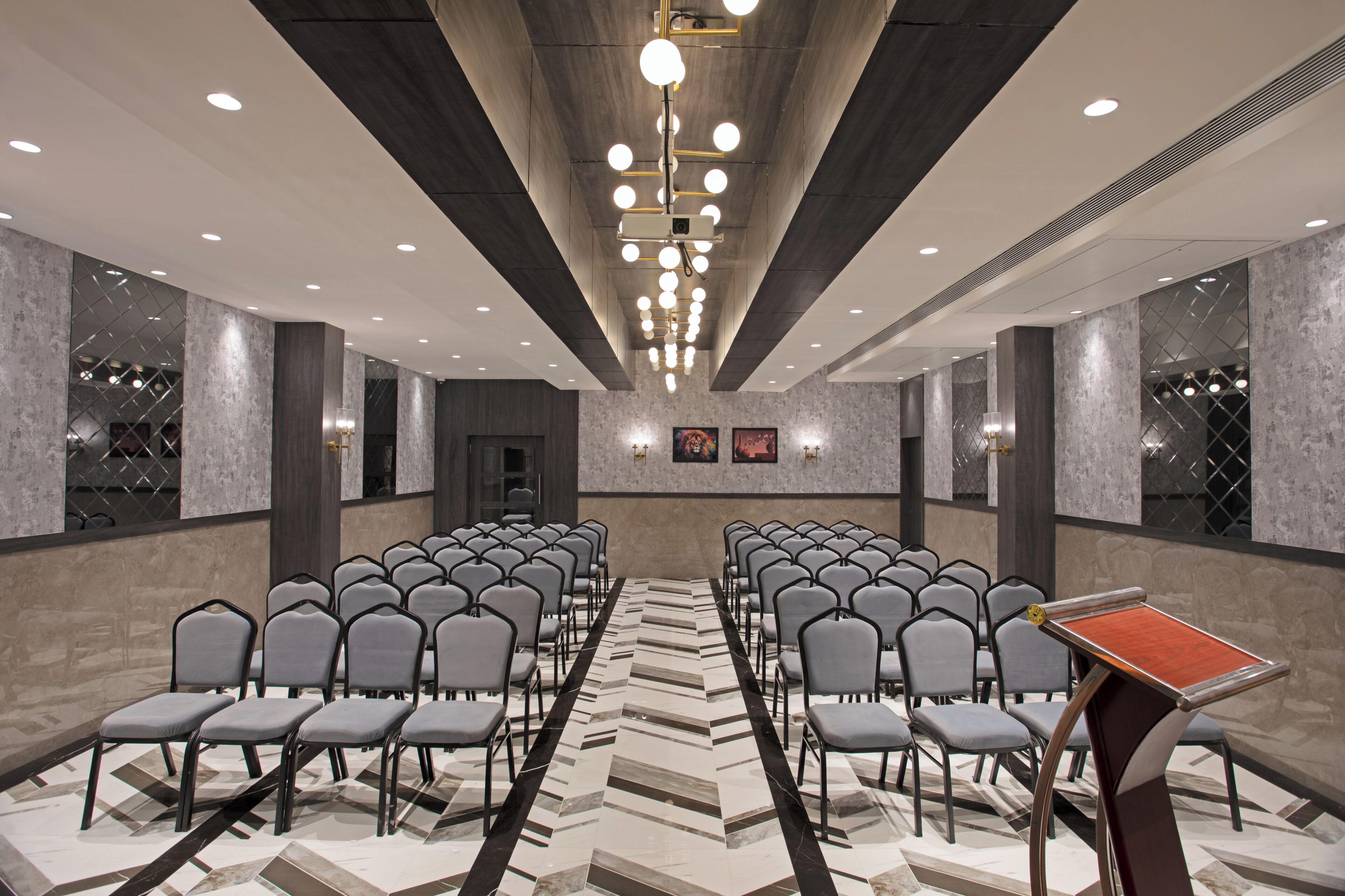 A conference room with rows of chairs, a projector screen, and a patterned floor.