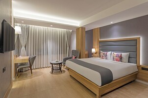 Una habitación de hotel con cama, escritorio, silla y una mesita redonda.