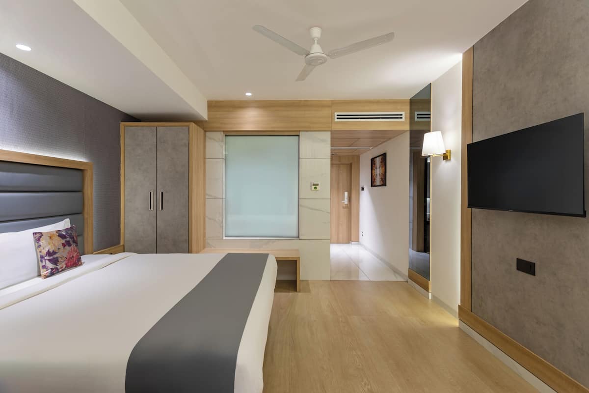 Una habitación de hotel moderna con cama, armario, televisión y ventilador de techo.
