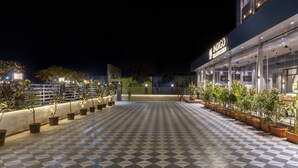 A nighttime view of a hotel with a checkered floor, potted plants, and a sign reading 'INDIGO.' - Hill Berry - A SoVo Hotel (Mawal)