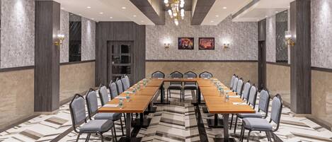 Un salón de conferencias con una larga mesa, sillas y un piso con diseño.