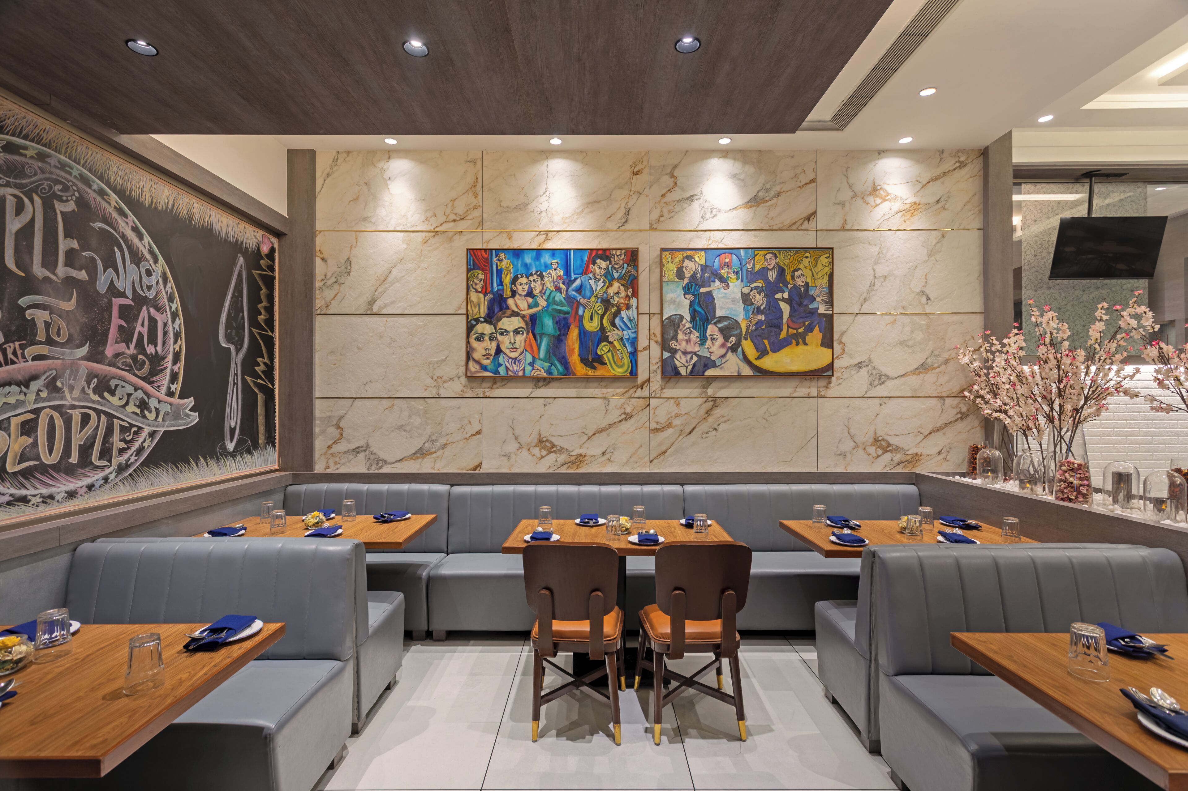 A restaurant with marble walls, artwork, and a seating area with tables and chairs.