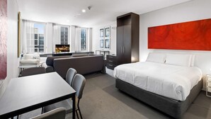 Een moderne hotelkamer met een bed, een bureau, een bank en een televisie.