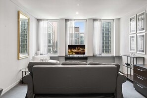 A modern hotel room with a large bed, a TV mounted on the wall, and a view of the cityscape through large windows. - Cosy Studio in the City Centre (Melbourne)