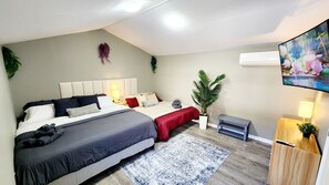 Een moderne slaapkamer met een groot bed, nachtkastjes, een flatscreen televisie en een potplant.