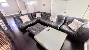Een modulaire bank met een afstandsbediening op een glazen salontafel in een woonkamer.