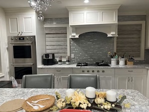 A modern kitchen with a built-in oven, a coffee maker, and a gas stove. - NONA Luxe 5BR 4BH  w/ Guesthouse / Theatre / GameRoom / Gym / Loft (Unknown)
