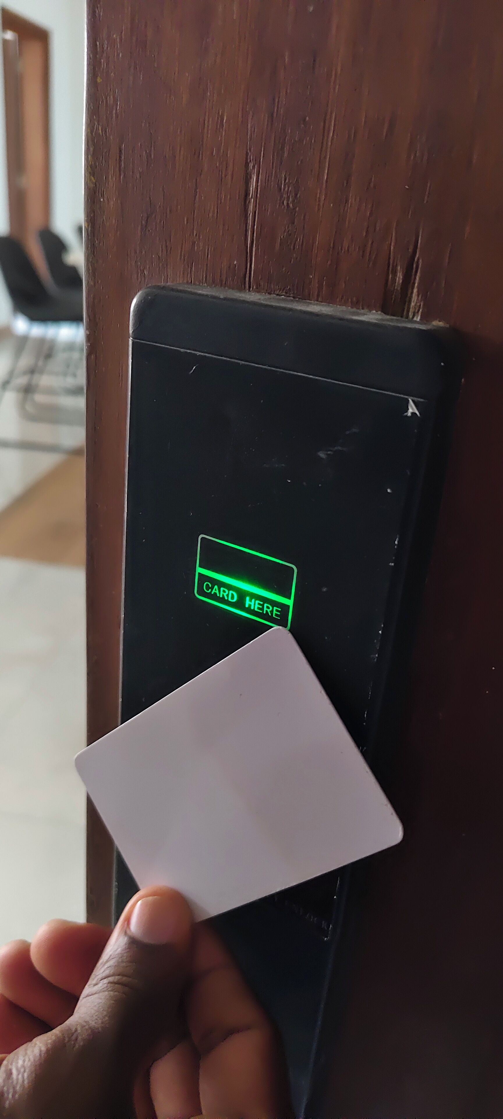 A hand holding a card near a card reader with a 'CARD HERE' sign.