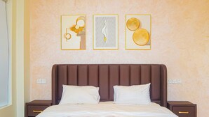 A hotel room with a large bed, two bedside tables, and three framed artworks on the wall. - Norden Suites (Mombasa)