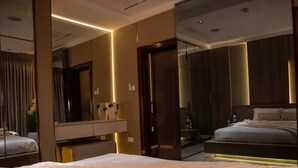Ett modernt hotellrum med en stor säng, ett sängbord, en spegel och en garderob.