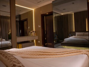 Ein modernes Hotelzimmer mit einem großen Bett, einem Nachttisch, einem Spiegel und einem Kleiderschrank.