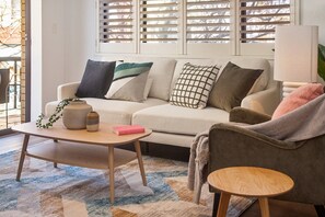 Ein Wohnzimmer mit einer Couch, einem Couchtisch, einem Beistelltisch und einer Lampe.