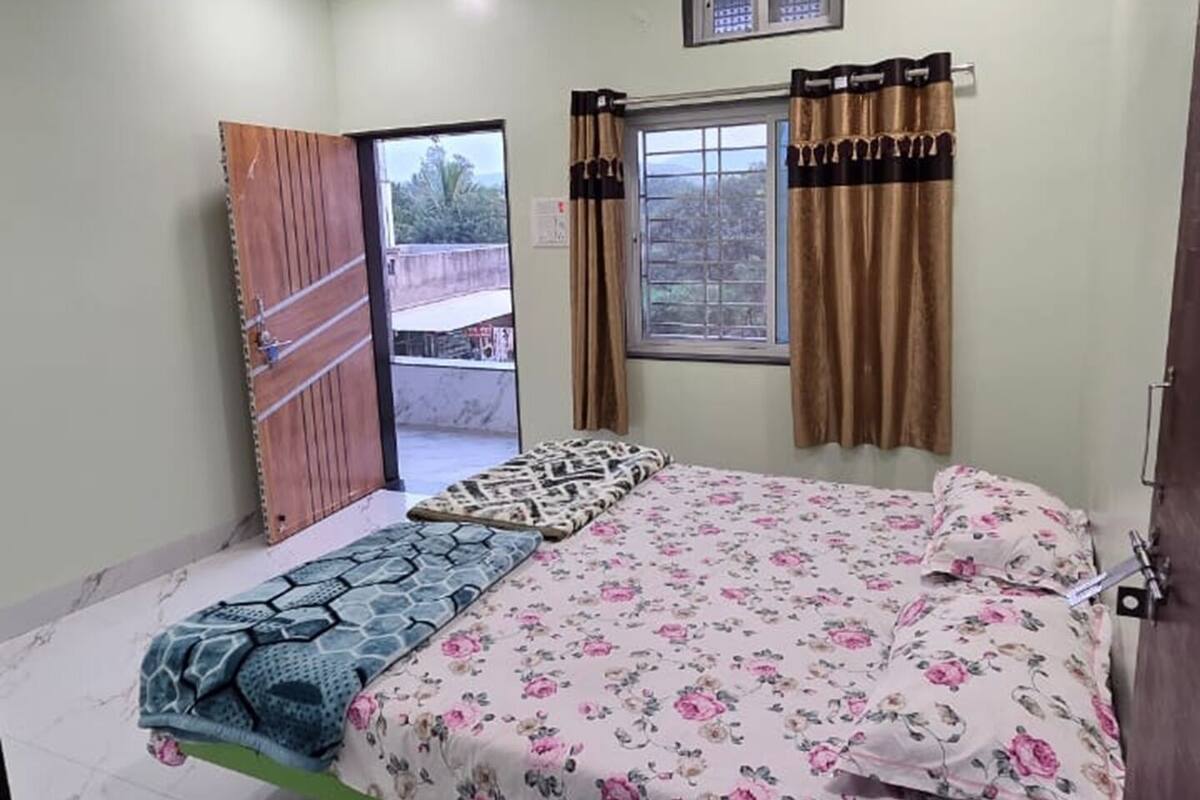 A bedroom with a bed, a ceiling fan, a window with curtains, and a door.