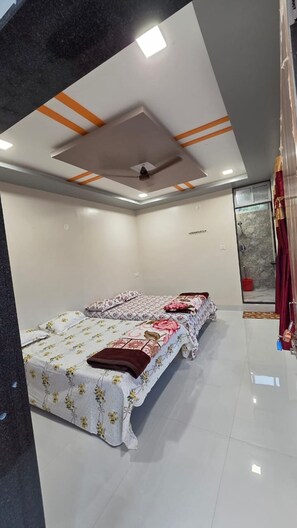 A bedroom with a bed, a ceiling fan, and a shower area. - Hotel Srivastava Residency & Restaurant (Ellora)