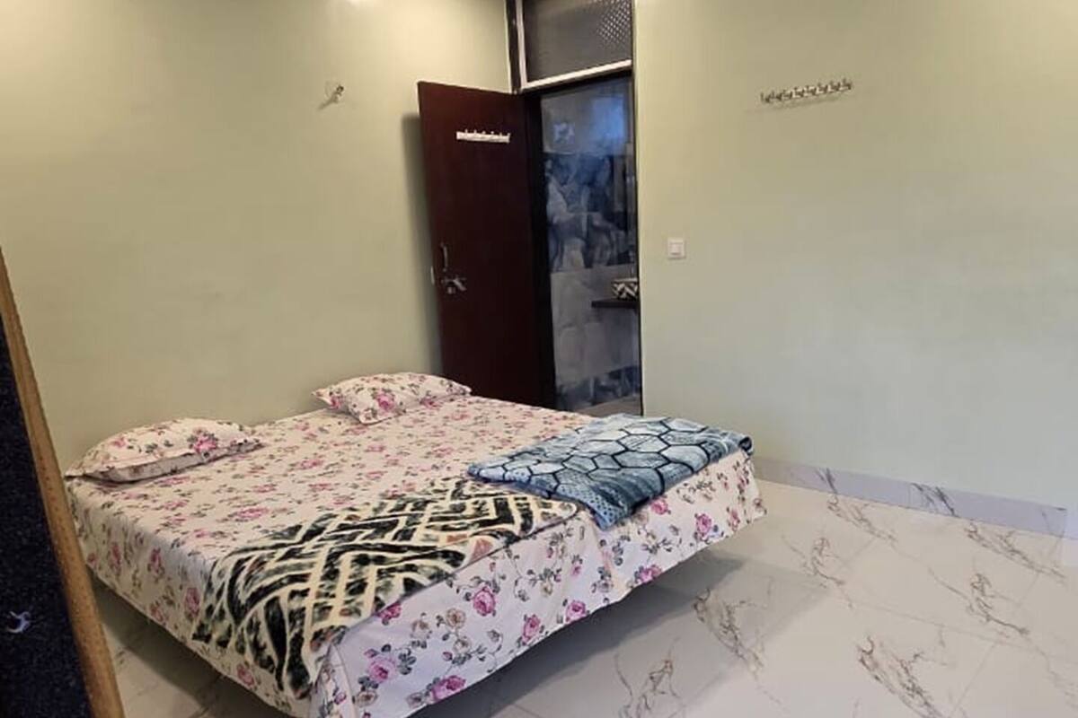 A bedroom with a bed, a ceiling fan, a door, and a tiled floor.