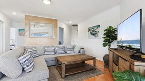 Un salon moderne avec un canapé, une table basse, un téléviseur et des œuvres d’art.