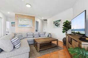 Ein modernes Wohnzimmer mit einer Couch, einem Couchtisch, einem Fernseher und Kunstwerken.