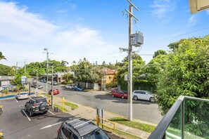 A parking lot with cars, a building with a red roof, and greenery. - Spacious and Superb 3-Bed Apartment (Bulimba)