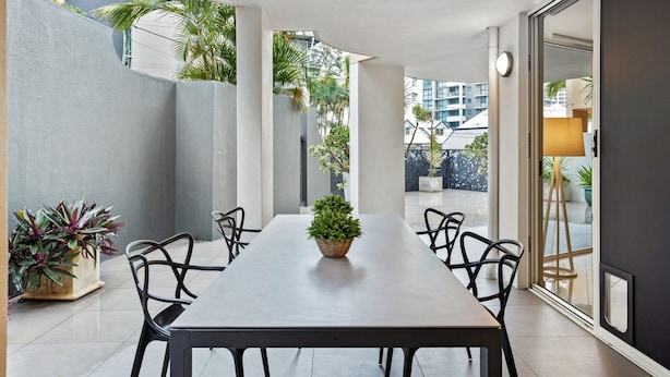 Un comedor moderno con una mesa larga, sillas negras y una planta en maceta.