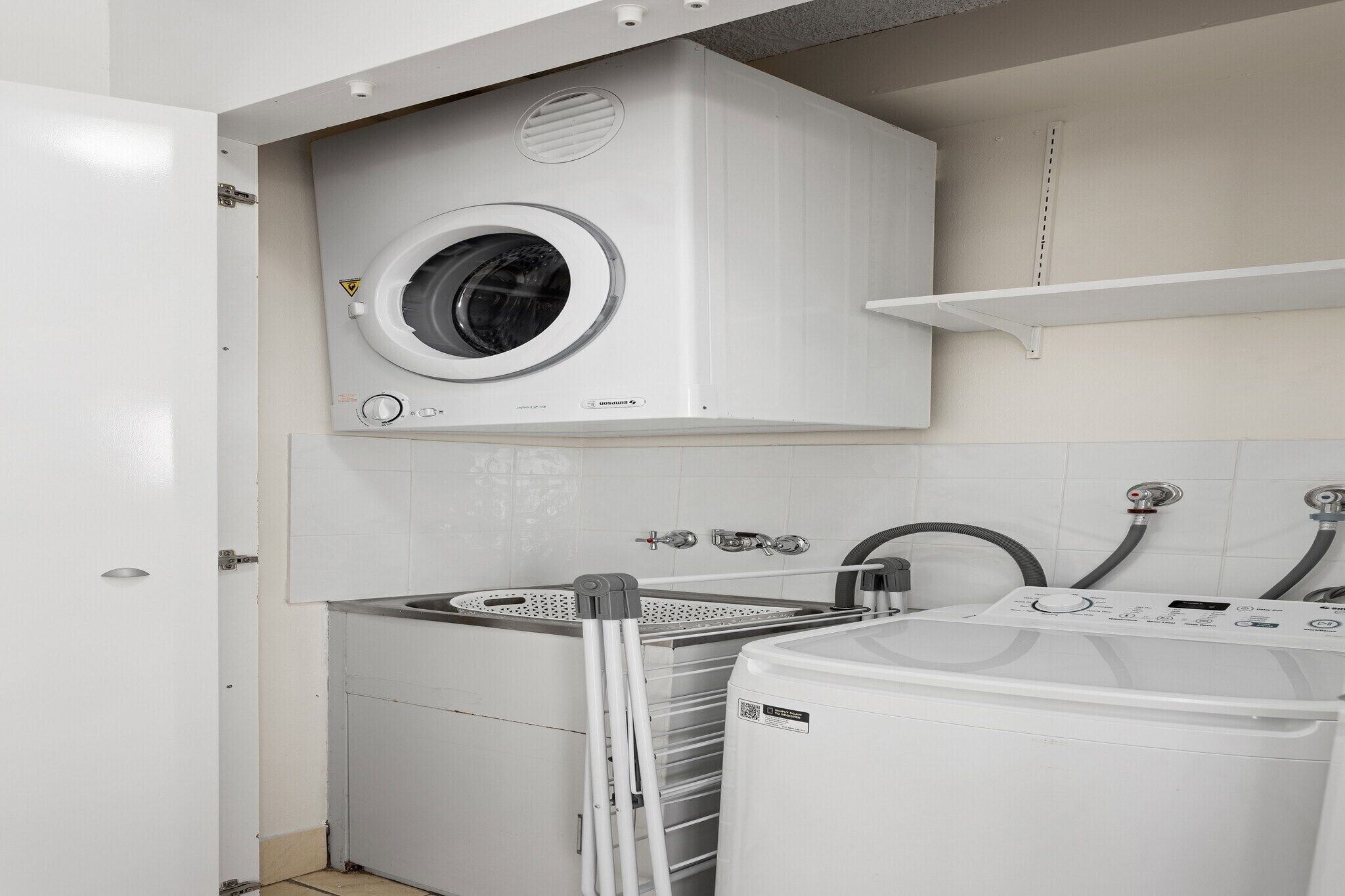 A laundry room with a front-loading washing machine, a dryer, and a utility sink.