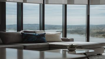 A modern living room with a sectional sofa, a coffee table, and large windows offering a view of a landscape.