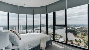 A bedroom with a large bed, a view of a river, and a cityscape.
