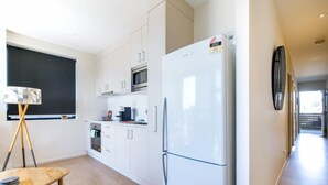Una cocina moderna con armarios blancos, un refrigerador blanco, un microondas y un comedor con mesa y sillas.