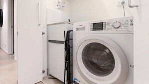 Una lavadora Bosch en una habitación de hotel con una puerta blanca y un refrigerador pequeño.