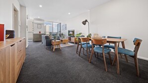 Uma sala de estar moderna com área de jantar, um armário de madeira e vista pela janela.