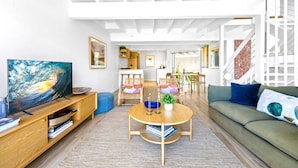 Una sala de estar moderna con televisión, muebles de madera, una mesa redonda y un sofá verde.