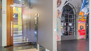 Un interior moderno con entrada por puerta de vidrio, lector de tarjeta de acceso y un mural con arte abstracto.