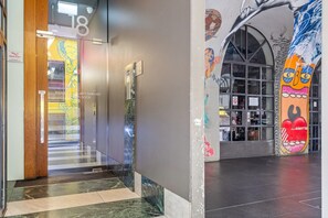 A modern interior with a glass door entrance, a security swipe card reader, and a mural with abstract art. - Sleek & Central 2-Bed Apartment in Melbourne (Melbourne)
