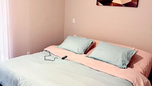 Un dormitorio con cama, almohadas, una obra de arte en la pared y un ventilador de techo.