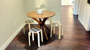 Un pasillo con una mesa redonda y dos sillas, un termostato en la pared y una puerta que da a otra habitación.