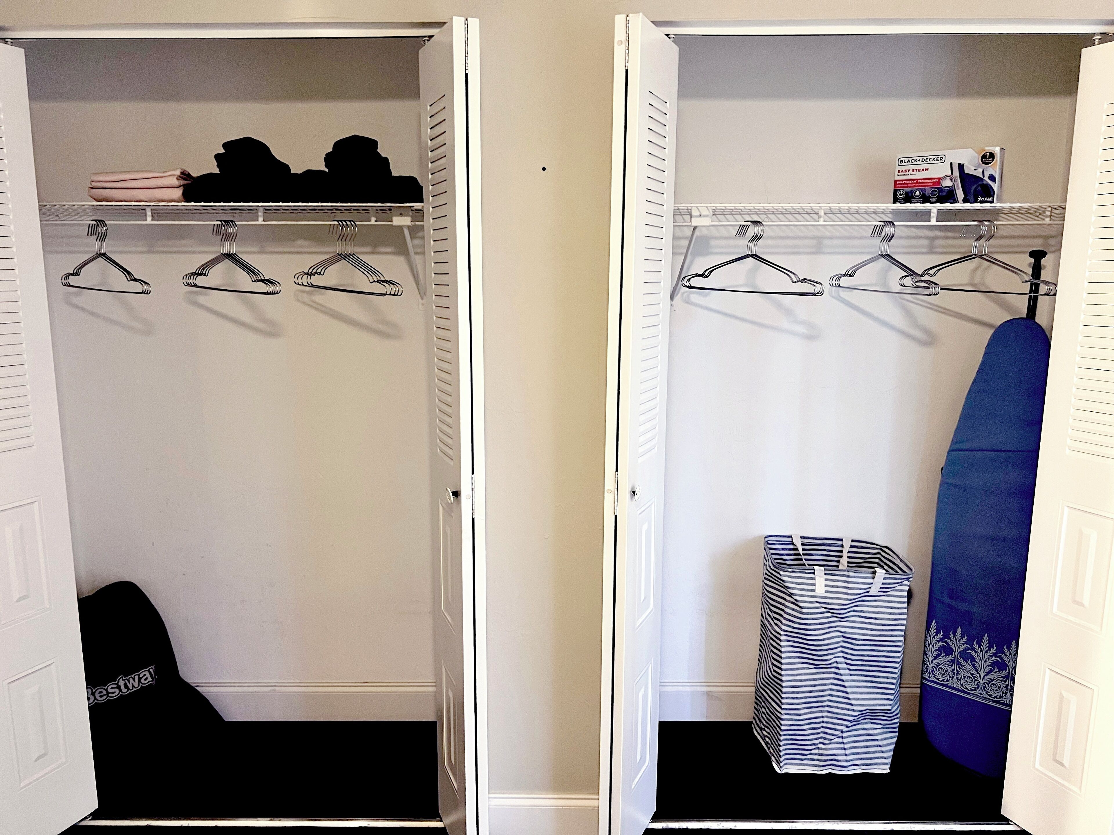 Deux placards ouverts, avec une tringle pour suspendre les vêtements, des étagères et un vêtement plié posé sur le sol.