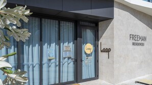 A modern building entrance with a glass door, a sign for 'Freeman Residences', and a yoga Pilates sign. - Fremantle 1-Bed Close to Beach & Shops (North Fremantle)
