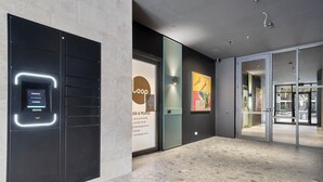 A modern interior with a reception area, a glass door entrance, and a poster advertising yoga & pilates. - Fremantle 1-Bed Close to Beach & Shops (North Fremantle)