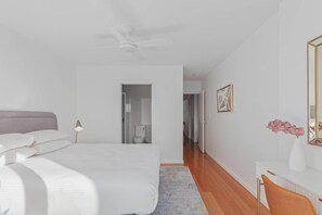 Una camera da letto con un letto, una scrivania, una sedia, uno specchio e una ventola a soffitto.
