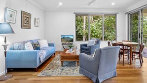 A modern living room with a sofa, armchair, coffee table, and dining table. - Quiet Ninderry Cottage with Peaceful Rural Outlook (Ninderry)