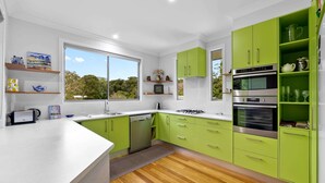 A modern kitchen with green cabinets, a white countertop, and a large window. - Quiet Ninderry Cottage with Peaceful Rural Outlook (Ninderry)