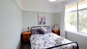 A bedroom with a bed, bedside tables, a lamp, a window with a view, and a ceiling light fixture.