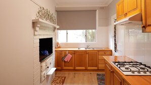 A kitchen with white cabinetry, a gas stove, a sink, and a window with a view.