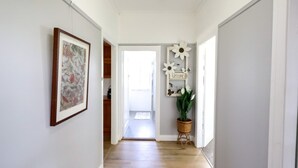 A hallway with a framed floral artwork, a welcome sign, and a potted plant.
