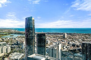 Ein Hochhaus mit moderner Glasfassade, umgeben von einer dicht bebauten Stadtlandschaft mit Blick aufs Meer.
