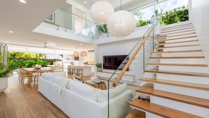 Ein modernes Interieur mit Treppe, Essbereich und Wohnzimmer mit Fernseher.