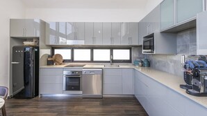 A modern kitchen with grey cabinets, a dishwasher, an oven, a sink, and a coffee machine. - Fun for Families: Location, Cinema, Games, Wifi (Leederville)