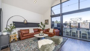 A modern living room with a sectional sofa, a coffee table, and a large window. - Fun for Families: Location, Cinema, Games, Wifi (Leederville)