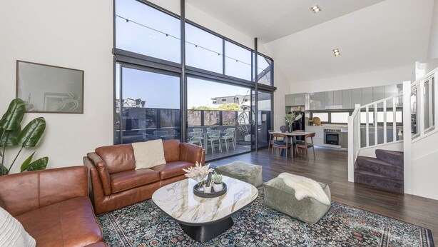 A spacious living area with a large window, a leather sofa, a marble coffee table, and a staircase leading to an upper level. - Fun for Families: Location, Cinema, Games, Wifi (Leederville)